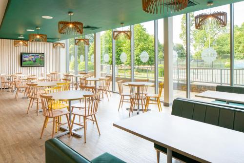 马洛Bisham Abbey National Sports Centre的餐厅设有桌椅和窗户。