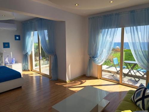 马佐托斯Villa Sunshine的一间卧室配有蓝色窗帘和大玻璃窗