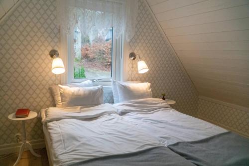 卢恩斯基尔Anfasteröd Gårdsvik - badstugor med loft的配有窗户的客房内的一张带白色床单和枕头的床