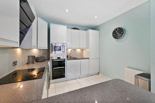 伦敦Hampstead Opulence Apartment - Luxurious Split Level Property的厨房配有白色橱柜和墙上的时钟
