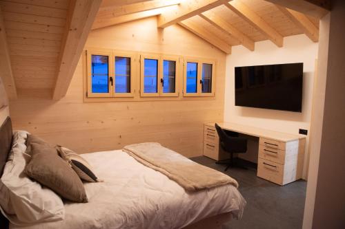GsteigChalet mit Kino und Jacuzzi in Gsteig b. Gstaad的一间卧室配有一张床、一张书桌和一台电视