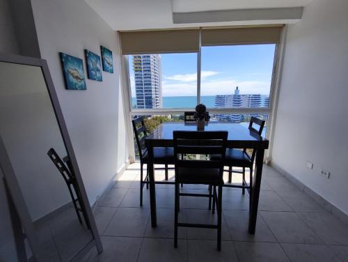 普拉亚科罗纳多Apartamentos en Playa Coronado的一间带桌椅和大窗户的用餐室