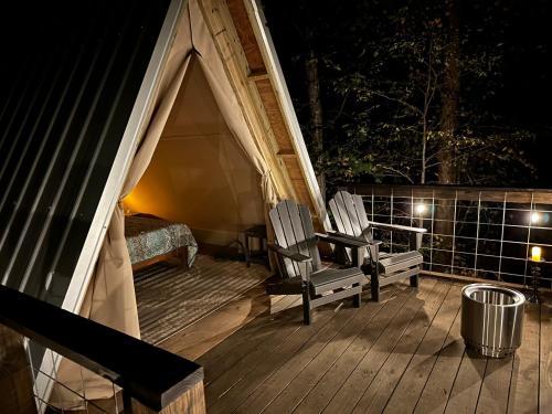 塔拉迪加Bohamia - Cozy A-Frame Glamp on 268 acre forest retreat的门廊配有两把椅子,晚上有帐篷