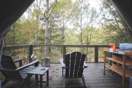 塔拉迪加Bohamia - Cozy A-Frame Glamp on 268 acre forest retreat的门廊配有两把椅子和一张桌子,位于甲板上