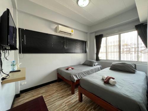 亚兰norndee hostel的一间卧室设有两张床、一台电视和一扇窗户。