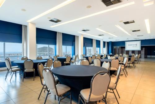 维多利亚维多利亚港金色郁金香酒店的一间会议室,配有桌椅和屏幕