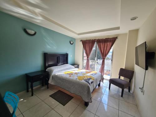 Paracho de VerduzcoHotel Santa Fe的一间卧室配有一张床、一张书桌和一个窗户。