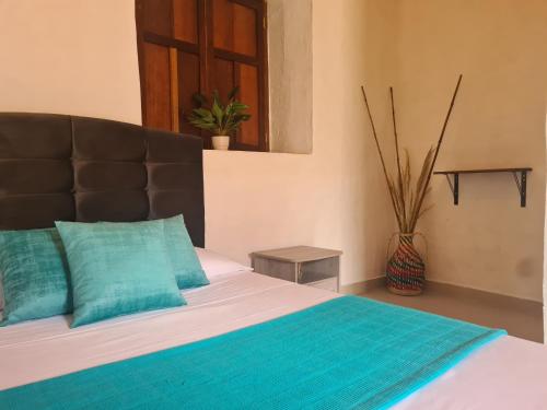 UticaHotel Alcázar Real的一间卧室配有一张带蓝色枕头的床和一扇窗户。