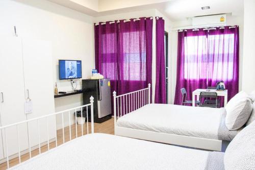 Ban Rong Khoei26bed and coffee的一间卧室配有两张床和紫色窗帘