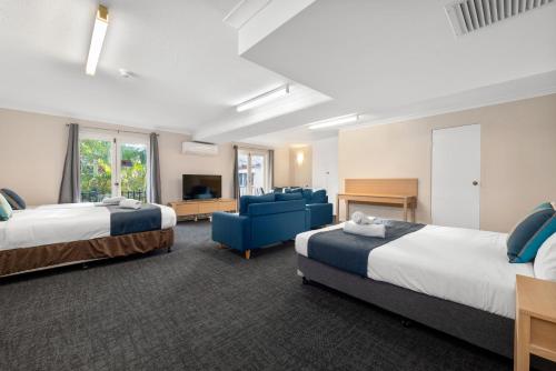 布里斯班Alloggio Hamilton Brisbane Airport的酒店客房,设有两张床和一张蓝色的沙发