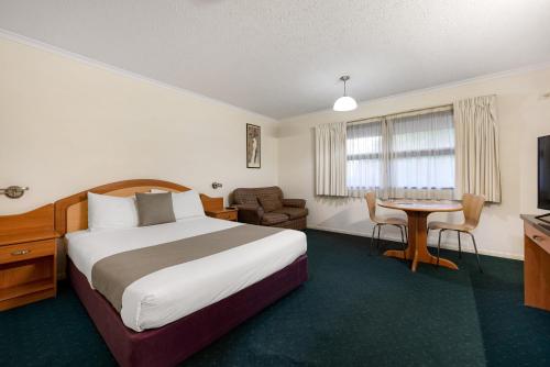 布里斯班飞马汽车旅馆及服务式公寓的酒店客房配有一张床铺和一张桌子。