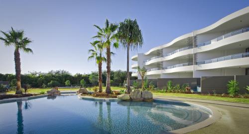 金斯克里福Cotton Beach Resort - Tweed Coast Holidays ®的棕榈树建筑前的游泳池