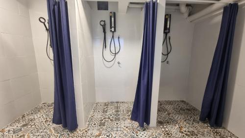 芭堤雅市中心Glur Hostel Pattaya Walking Street的浴室设有蓝色淋浴窗帘,铺有瓷砖地板。