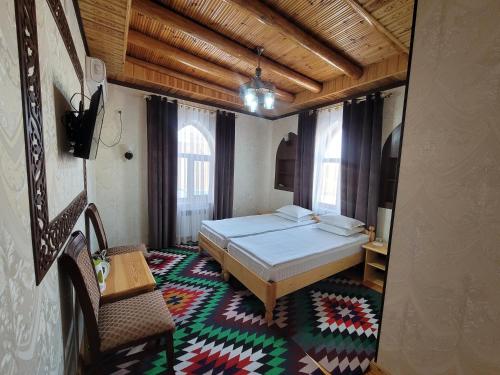 希瓦Khiva Siyovush Hotel的卧室配有1张床、1张桌子和1把椅子