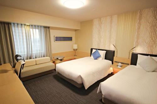 川崎尊贵武藏小杉里士满酒店的酒店客房,设有两张床和一张沙发