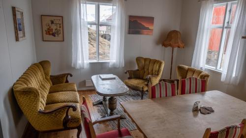 Djupavik迪居帕威客酒店的客厅配有椅子和桌子,设有窗户