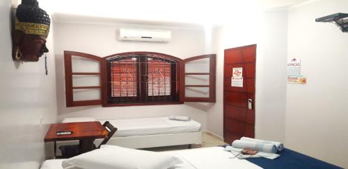 圣塞巴斯蒂安Pousada Estrela Mare的客房设有两张床、一张桌子和一扇窗户。