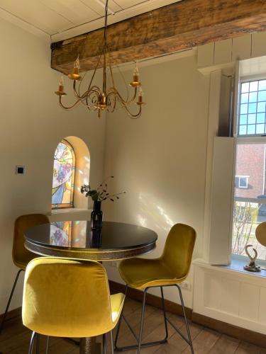 温斯霍滕Zeer sfeervol gastenverblijf in Het Molenhuisje met woonkamer en keuken的用餐室配有圆桌和黄色椅子