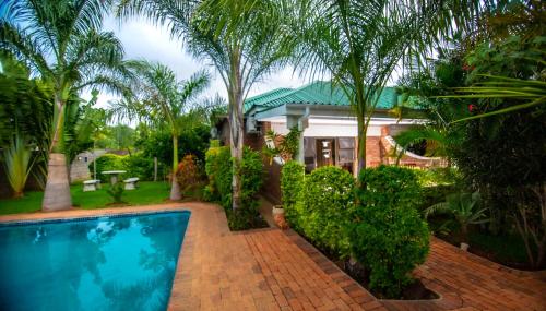 维多利亚瀑布Dzimbahwe Guest Lodge的一座带游泳池和棕榈树的房子