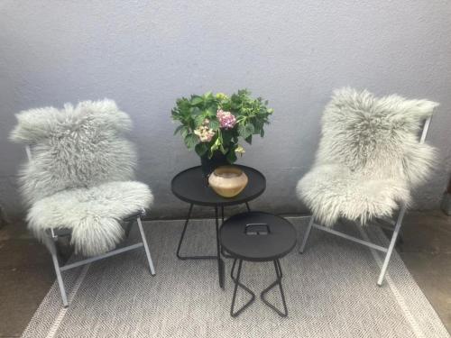 吕贝克Modernes, familienfreundliches Apartment in Lübeck的三把椅子,带毛绒座椅,一张带花瓶的桌子