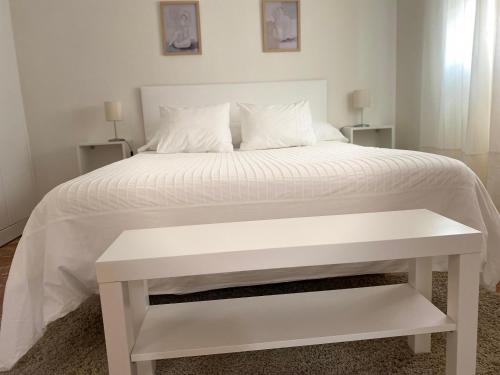 埃希哈APARTAMENTO PLAZA ESPAÑA的一张白色的床,旁边是白色长凳