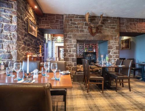DirletonThe Castle Inn的餐厅设有木桌和椅子,拥有砖墙