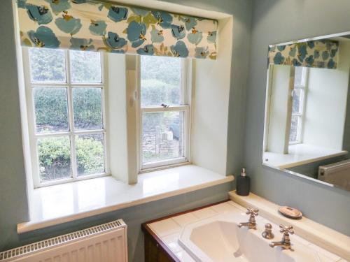 奥尔德姆Hawkyard's Cottage的一间带水槽的浴室和两个窗户