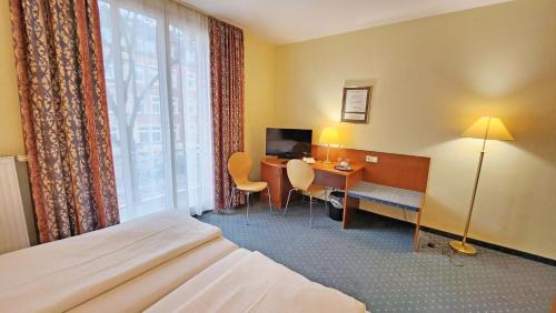 德累斯顿Hotel Amadeus Dresden Neustadt的配有一张床、一张书桌和一扇窗户的酒店客房