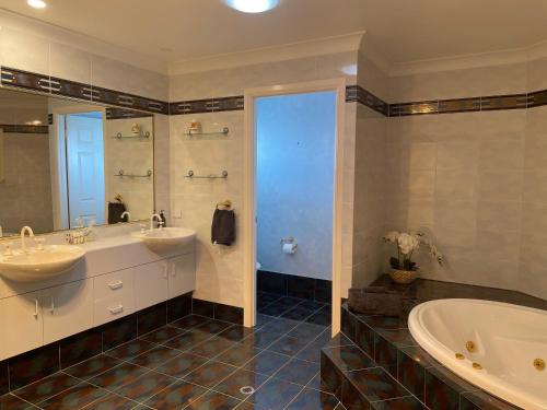 Banksia BeachSPECTACULAR WATERFRONT Canal Home, BRIBIE ISLAND的大型浴室设有两个盥洗盆和浴缸。