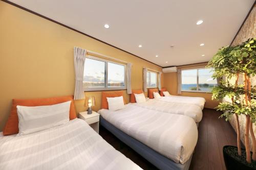 白滨Crystal Besso Uminomachi的带窗户的客房内的三张床