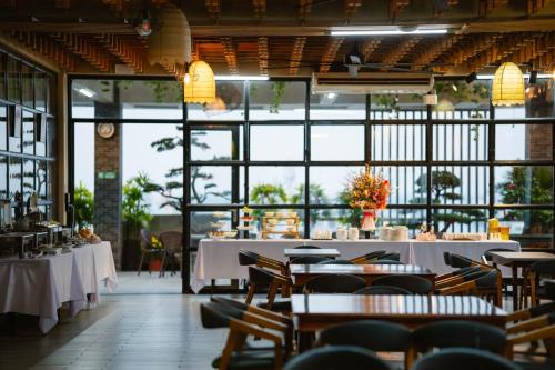 龙川市LARA HOTEL LONG XUYÊN的餐厅设有白色的桌椅和窗户。