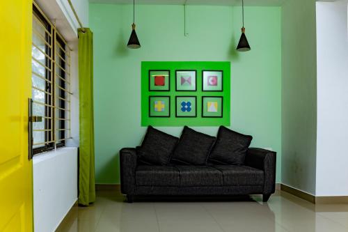 科泽科德Ecoville suites的绿色墙壁的房间里一张黑色的沙发