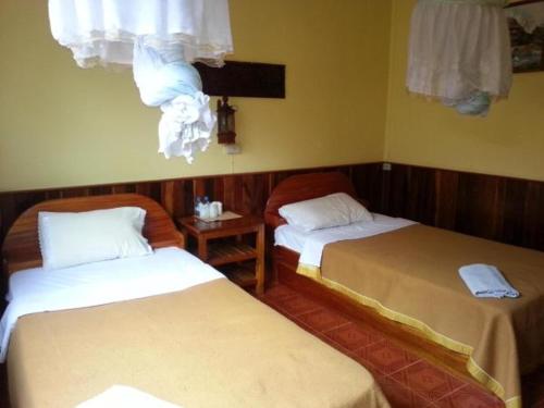 Muang KhôngPon's Riverside Guesthouse的客房设有两张床和一个带窗帘的窗户。