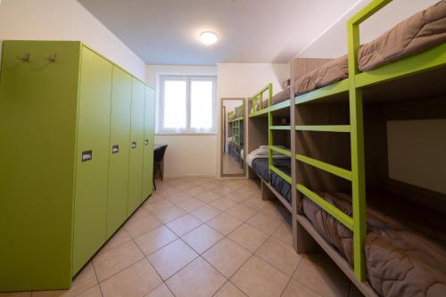 罗韦雷托Ostello Città di Rovereto的一间设有绿色双层床和走廊的客房