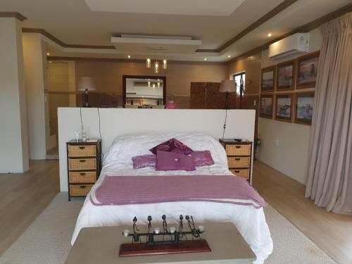 MatsaphaGoggas Nest BNB & Restaurant的卧室配有一张带紫色枕头的大型白色床。