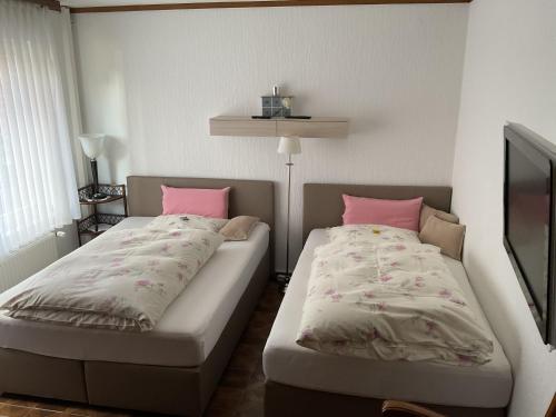 内特塔尔Fewo An der Mühlenbachaue的一间卧室配有两张带粉红色枕头的床