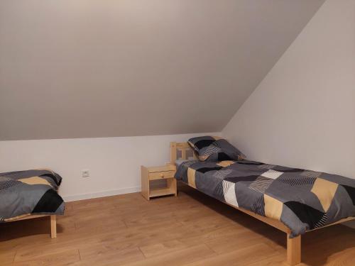 克拉科夫Pokoje Kraków Tyniec的配有白色墙壁和木地板的客房内的两张床