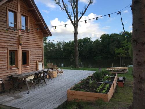 FeingsLa cabane de l'étang的木甲板上设有野餐桌和房屋