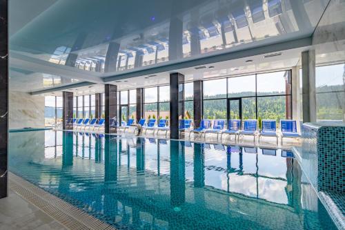 布克维Elena Spa Resort的大楼内带蓝色椅子的大型游泳池