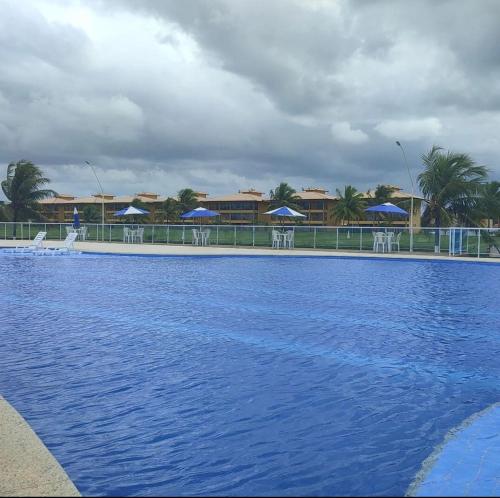 埃斯坦西亚Resort Villa das águas praia do saco的一大片蓝色的海水,有桌子和遮阳伞