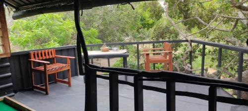 Bundala LevagamgodaJungle Cabin的阳台配有两把椅子、一张桌子和一张桌子