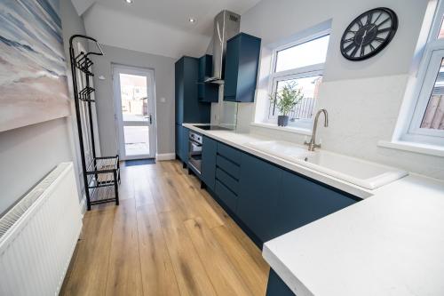 克利索普斯Highgate Beach House的厨房配有蓝色橱柜、水槽和窗户。