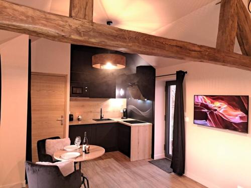 Saint-Denis-de-JouhetLa bergerie cosy - Sauna et bain nordique privatif的一间带桌子的房间和一间带柜台的厨房