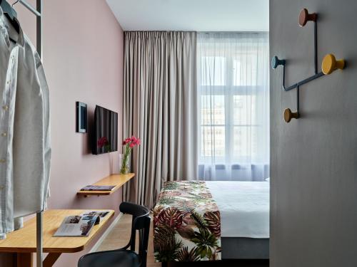 格丁尼亚HOLA GDYNIA的配有一张床、一张书桌和一扇窗户的酒店客房