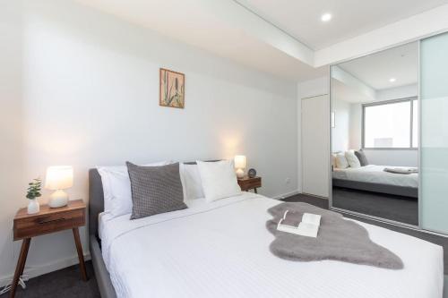 悉尼Cozy 2BR w Free Parking Near Westfield Parramatta的卧室配有一张白色大床和镜子