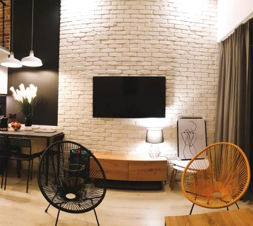 斯维诺乌伊希切Lividus Czarna Mewa的客厅配有两把椅子和砖墙上的电视