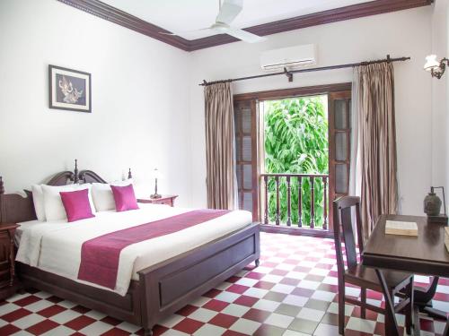 暹粒吴哥城堡住宿酒店的一间卧室配有一张床、一张书桌和一个窗户。