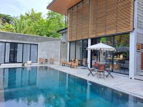 班图尔DJipangan Home的一座房子,设有一座带桌子和遮阳伞的游泳池