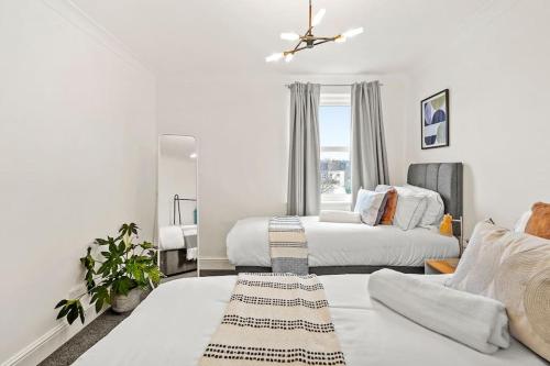 伦敦5 guests 3 beds 1 sofa bed Lewisham的一间白色卧室,配有两张床和镜子
