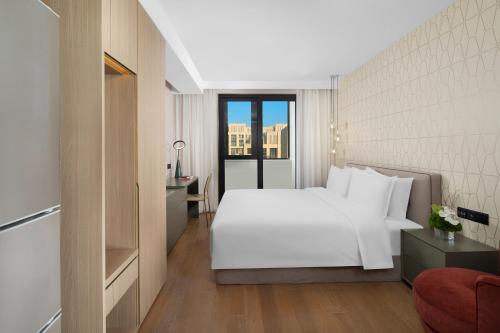 上海临港东缦国际公寓的卧室设有一张白色大床和一扇窗户。